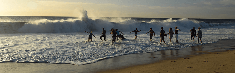 Students running into the surf on the beach